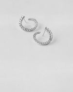 Silver hoop earrings with clear stones on a light gray background
